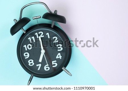 Flat lay vintage alarm clock on sweet pastel colored paper top view, background texture, pink, purple, yellow, beige, green and blue colour.