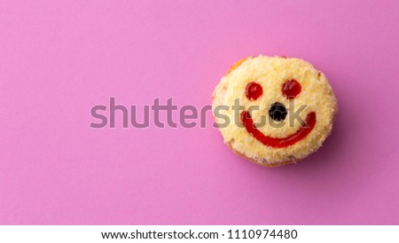 Close up of yellow smiley happy face donut isolated on pink background