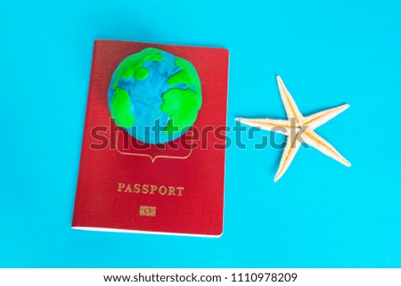 Travel concept, plasticine earth, passport and starfish on the blue background. 