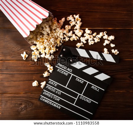 Cinema background. Film watching. Popcorn and clapperboard on wooden planks with copy space