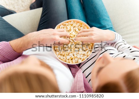 Ginger red hair people snack happiness friendship concept. Top overhead pov close up view of two lovely charming cute carefree lovers watching cartoons on tv eating pop-corn from big box sitting divan