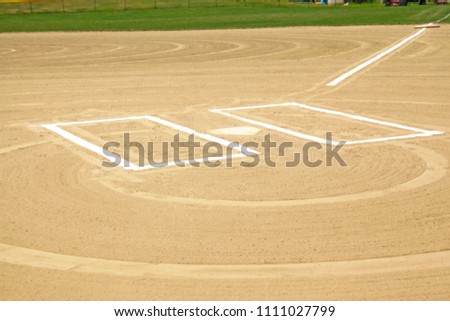 Close ups of dirt baseball diamond from a public park with newly painted baselines and batters box. 