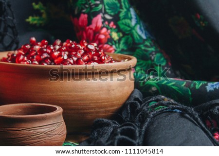 still life fruits and seeds of pomegranate in earthenware on the background of a traditional scarf with patterns. traditional Ukrainian dishes
