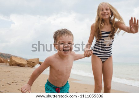 Brother and sisters are playing with sand on the beach. Lifestyle photo