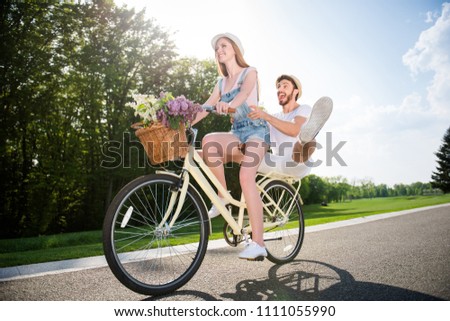 He vs she together forever! Portrait of cheerful positive couple outdoor, beautiful red head woman riding on bike with handsome crazy man on trunk holding legs up. Extreme adrenalin concept