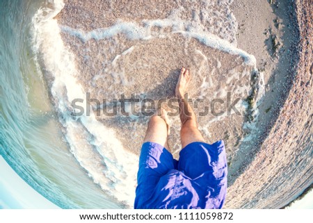 Feet in the sea water. Men's feet on the sandy shore. Selfy near the ocean shore.