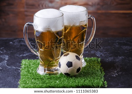 Image of two glasses of beer, soccer ball on green grass