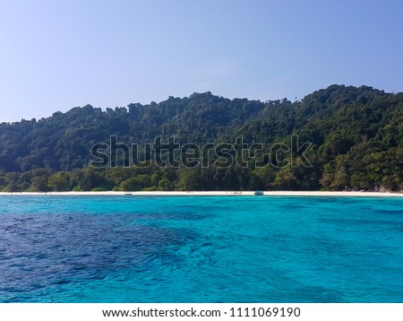 Clear blue sea, sandy beach in front of beautiful mountain.