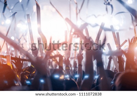 silhouettes of hand in concert.Light from the stage.confetti.the crowd of people silhouettes with their hands up.ribbon
