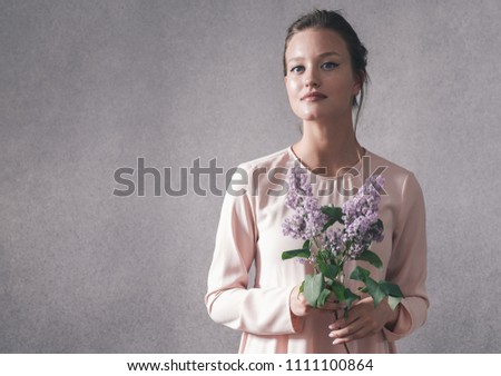Woman with lilac flower over gray vintage background