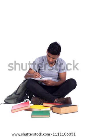 Young man wearing a casual outfit, sitting crossed legs on the ground, there many books on the ground he is doing his homework, isolated on white background.