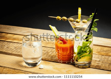 martini and bloody mary drink and water and hangover pills on a wooden table