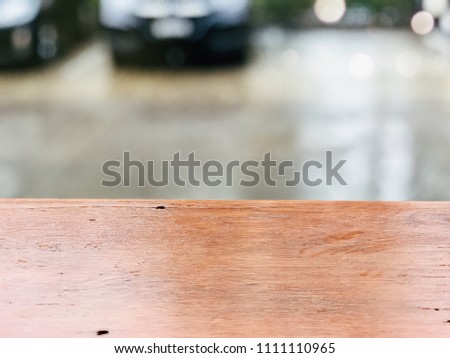 Empty brown wooden table and car parking blurred background with bokeh image. For product display montage.
