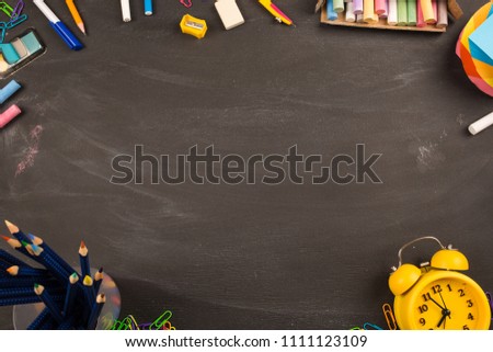 bright office supplies, yellow alarm clock on black chalkboard top view, copy space. concept: back to school, school's out, school holidays, teacher's day