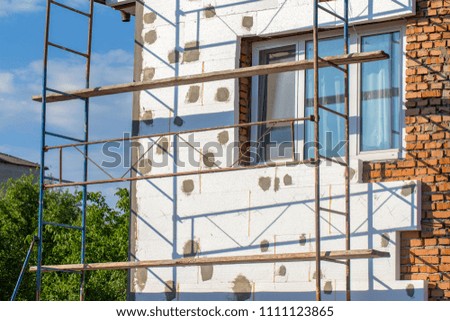 Scaffold on house, renovation. House for renovation with the scaffolding for workers on building, close up