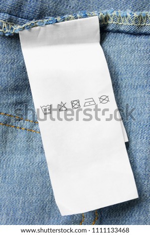 Care clothes label on blue denim background closeup