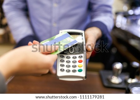 Photo of buyer man with bank card and seller with terminal in hand
