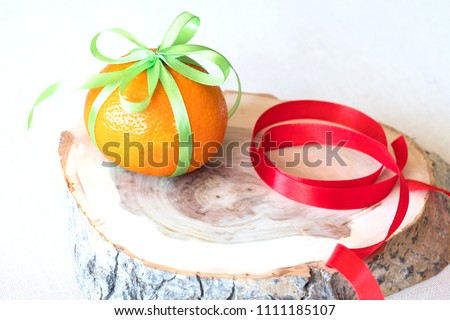 on the stump is an orange with a gift ribbon, a red ribbon on a stump