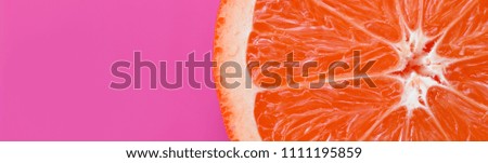 Top view of an one grapefruit slice on bright background in purple color. A saturated citrus texture image