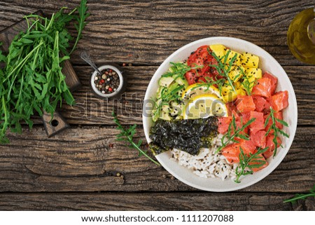 Hawaiian salmon fish poke bowl with rice, avocado, mango, tomato, sesame seeds and seaweeds. Buddha bowl. Diet food. Top view. Flat lay
