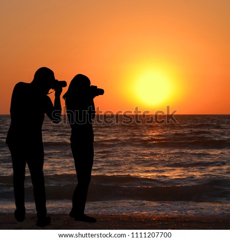 Silhouette of man and woman photographers take a sunrise picture