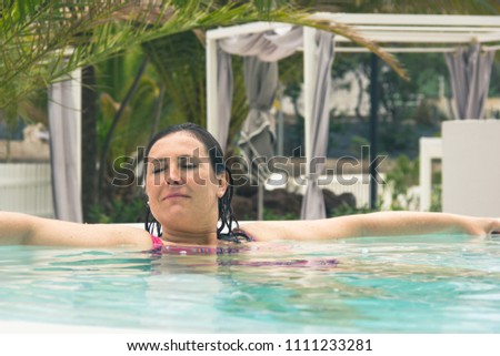 Smiling woman enjoying leisure time in hot tub. Young lady resting in swimming pool with eyes closed. Summer dream vacation, chill out mode, peaceful holidays concept. Vintage effect