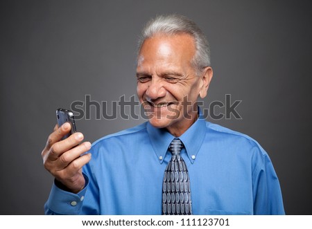 Older Businessman laughs at text message