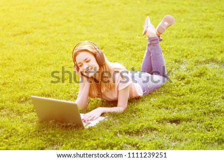 Girl in a laptop listening to music in headphones in the Park
