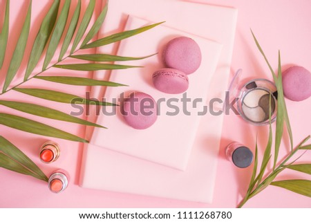 Flatlay of notebook, cake macaron, flower on pink table. Beautiful breakfast with macaroon