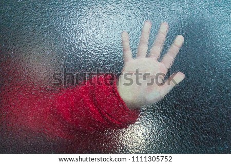 Child's hand through the frozen glass