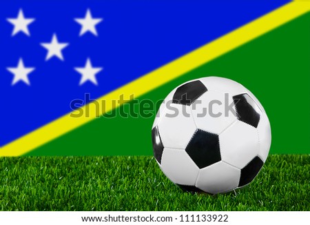 The Solomon Islands flag and soccer ball on the green grass