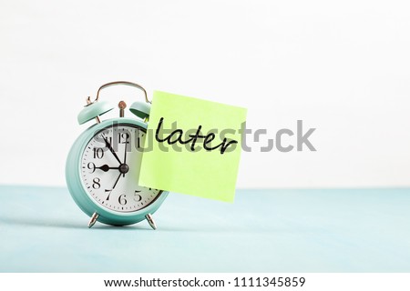 Procrastination, delay and urgency concept. Bad time management. Word later sticked to alarm clock Royalty-Free Stock Photo #1111345859