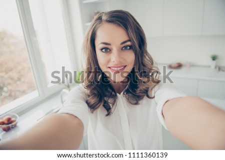 Self portrait of charming trendy lovely cute woman in shirt shooting selfie on front camera with two hands having video call with her lover