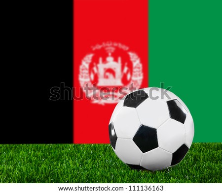 The Afghan flag and soccer ball on the green grass