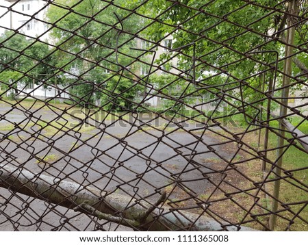 Broken steel mesh of metal fence of a basketball court in residential neighborhood ,Tennis or basketball court behind fence mesh netting at school.