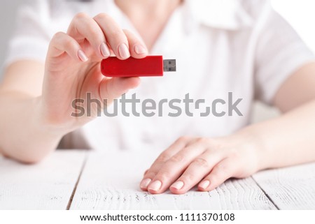 Female hold flash drive in hand on white table