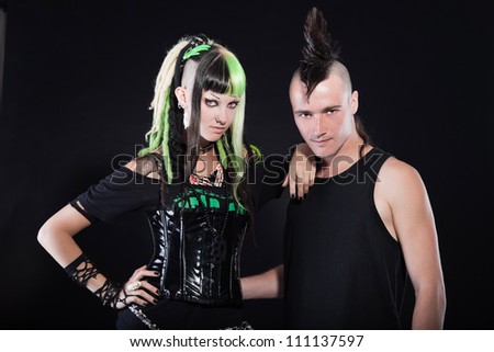 Couple of cyber punk girl with green blond hair and punk man with mohawk haircut. Expressive faces. Isolated on black background. Studio shot.