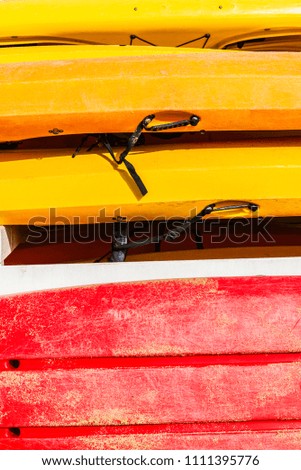Heap of red and yellow kayaks or boats of plastic as abstract background