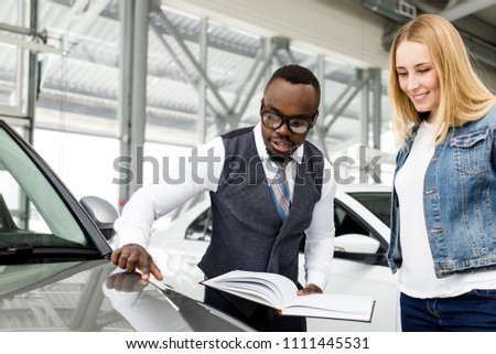 Car salesman helps client to choose a new car in the dealership