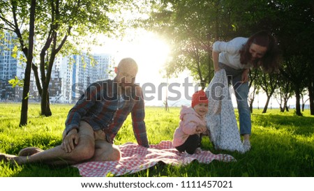 Happy family on a picnic with a child resting on nature at sunset in the park.