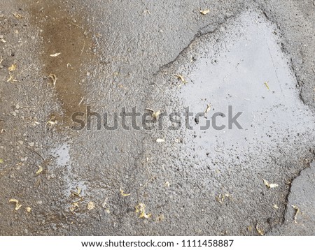 water puddles with raindrops and water circles on cracked wet asphalt road