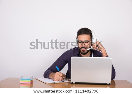 Young call center employee taking orders writing on the clipboard on a grey background.