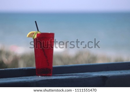 Perspective photography of cold refreshing drink on wooden bar ledge at outdoor beach patio restaurant. 