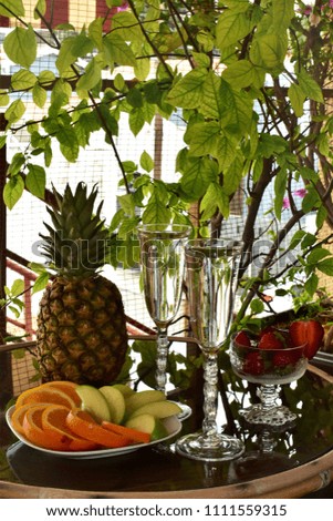 Citrus water in a tall glasses and summer fruits, on a veranda table, vertical banner.