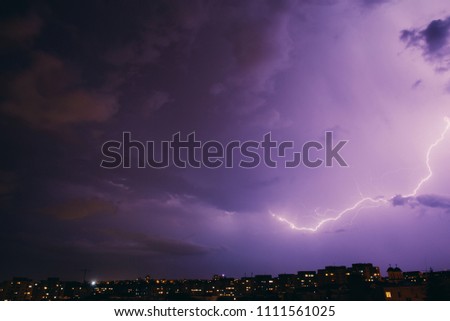 City view at night under thunderstorm with strike of lightning. Bad weather. 