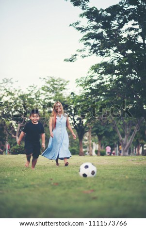 Little boy playing soccer football with mother in the park