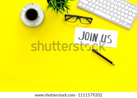Template for contacts. Hand lettering Join us on work desk with glasses, coffe, plant, computer keyboard on yellow background top view copy space