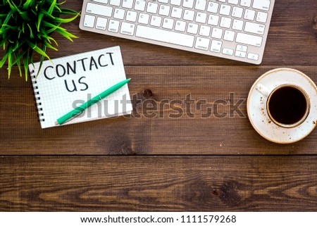 Template for contacts, background for contact information. Lettering Contact us in notebook on office work desk with computer on dark wooden background top view space for text