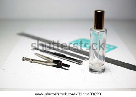 Equipment for workshop packaging design and development with glass bottle for cosmetics or product. Selective focus on compasses.
