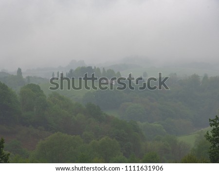 Misty morning landscape in French Basque country. Traditional farmhouse building and hills hiding in the fog.